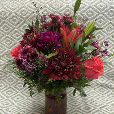 Mixed bouquet of burgundy and pink flowers in a glass vase