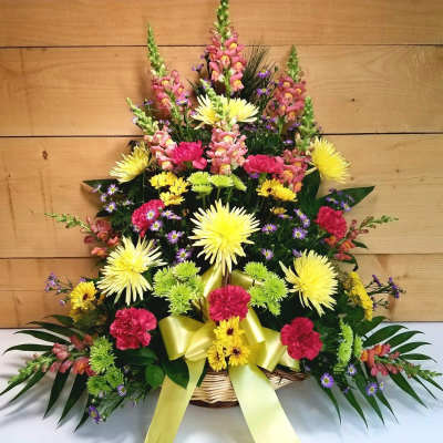 Basket arrangement of yellow, pink, and green flowers with a yellow ribbon