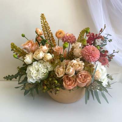 Peach and white floral arrangement in a low beige bowl