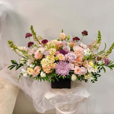 Large pastel floral arrangement in a black rectangular container