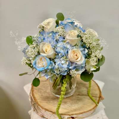 Blue hydrangea and cream roses in a clear glass vase