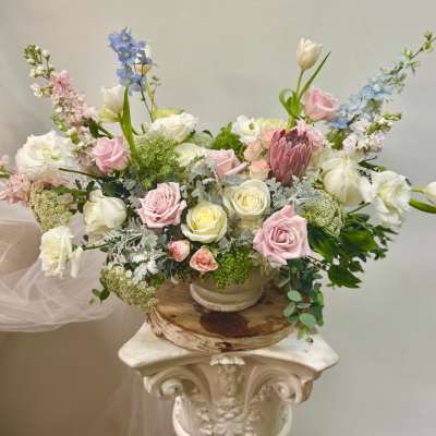 Pastel floral arrangement with roses, tulips, and delphinium in a low bowl