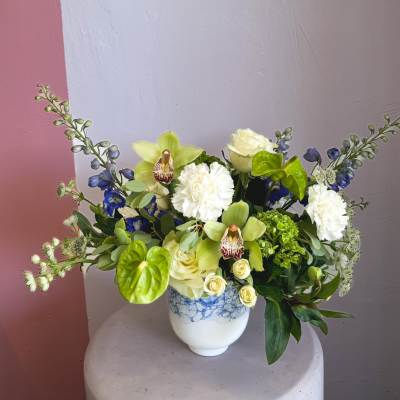Mixed bouquet in a white vase with pale green orchids and white blooms