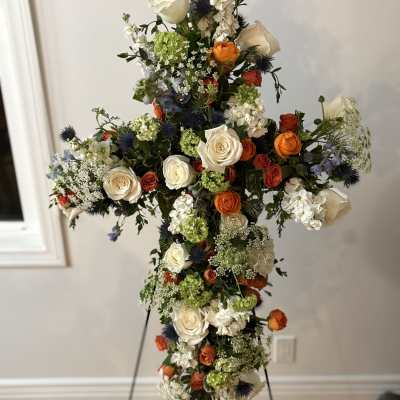 Tall floral cross with white, orange, blue, and green flowers