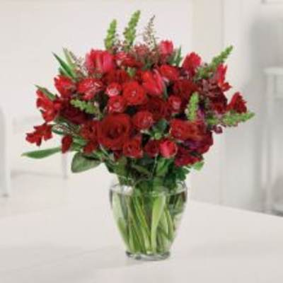 Red mixed flower bouquet in a clear glass vase