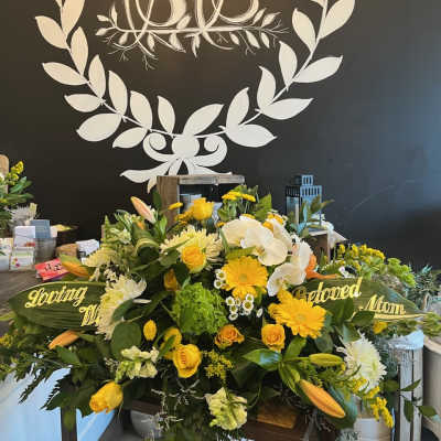 Yellow and white sympathy floral arrangement with roses, lilies, and orchids