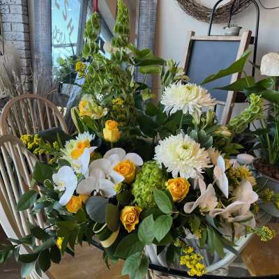Large floral arrangement with white orchids, yellow roses, and white chrysanthemums