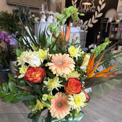 Mixed bouquet with peach gerberas, orange roses, and white daisies in a glass vase
