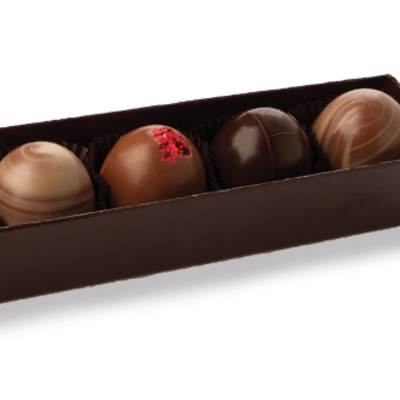 Row of six assorted chocolate truffles in a long dark brown box