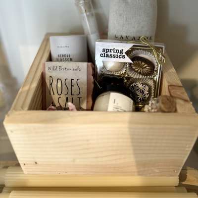 Gift basket with soaps, candles, and chocolates in a wooden crate