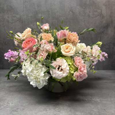 Pastel floral arrangement in a low vase with roses, hydrangeas, and carnations