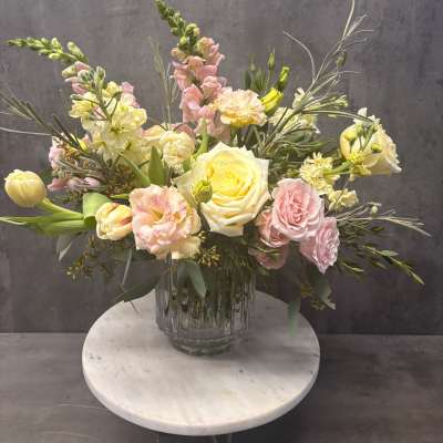 Pastel bouquet of roses, tulips, and snapdragons in a glass vase