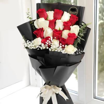Bouquet of red and white roses wrapped in black paper with a white ribbon
