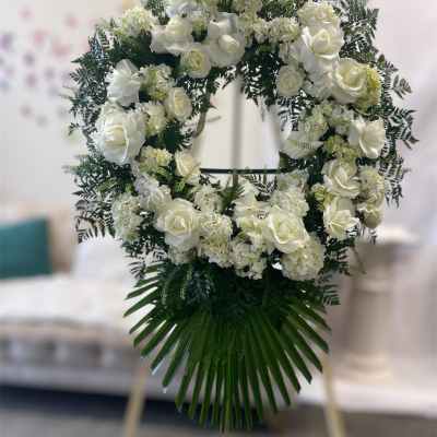White rose and hydrangea funeral wreath on an easel