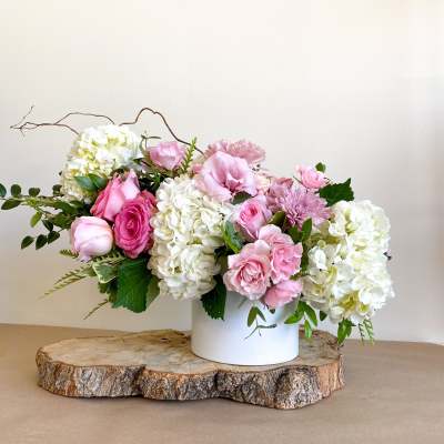 Pink roses and white hydrangeas arranged in a white vase