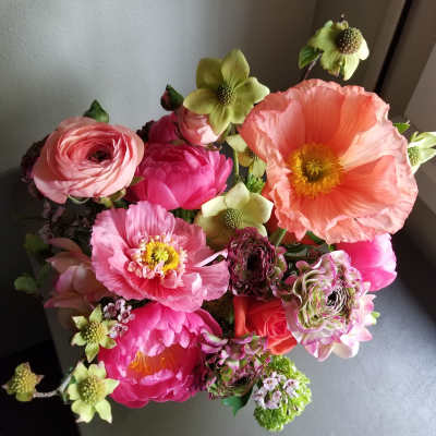 Top view of a bright pink and peach flower arrangement with large poppies and ranunculus