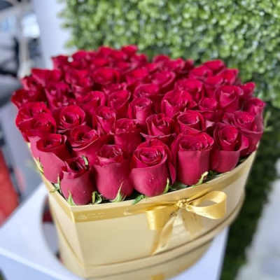 Heart-shaped gold box filled with red roses and tied with a gold ribbon