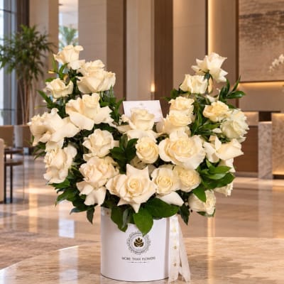Cream rose arrangement in a white hatbox with a ribbon