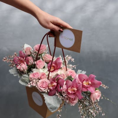 Pink roses and orchids in a brown handled gift bag