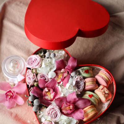 Heart-shaped red box with pink flowers and pastel macarons