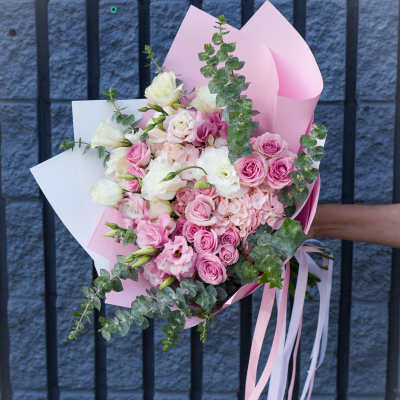 Pink and white bouquet of roses and lisianthus wrapped in pastel paper