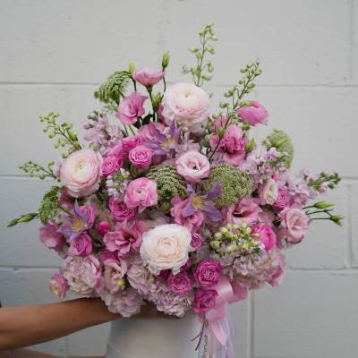 Pink and white mixed flower bouquet in a white vase with ribbon