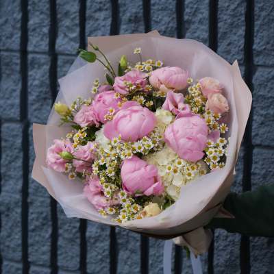 Pink bouquet with white daisy-like flowers wrapped in pale paper
