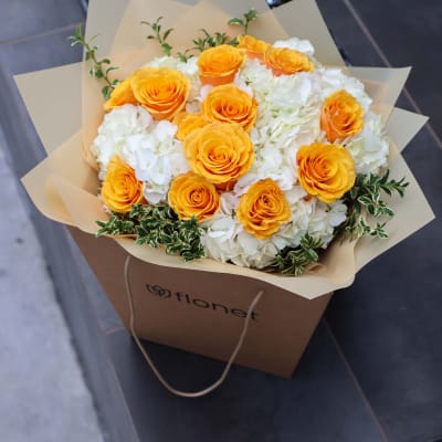 Bouquet of orange roses and white hydrangeas in tan wrapping