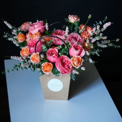 Pink and peach roses arranged in a kraft paper gift bag
