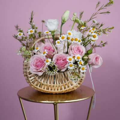 Pink roses and white daisies in a woven basket