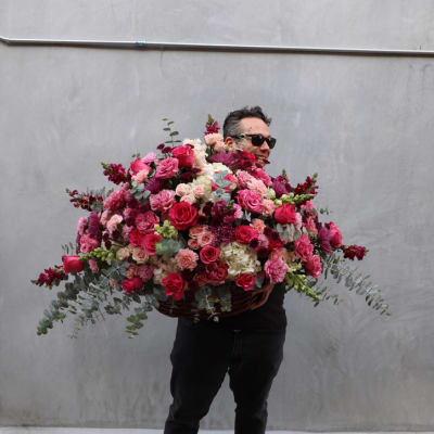 Man holding a huge mixed pink and red flower arrangement
