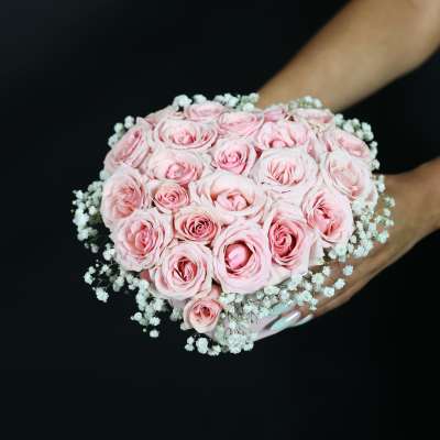 Handheld bouquet of pale pink roses with white baby's breath