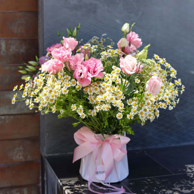 Pink roses and white daisies in a white box with a pink ribbon