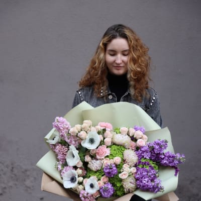 Woman holding a large pastel bouquet of pink, purple, and white flowers