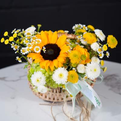 Basket arrangement with a sunflower and white daisy-like flowers