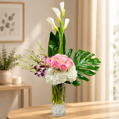 Tall vase arrangement with pink roses, white hydrangea, and white calla lilies