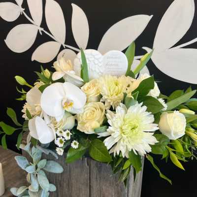 White floral arrangement in a rustic wooden box with orchids and roses