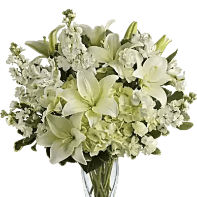 White lilies and white filler flowers in a clear glass vase
