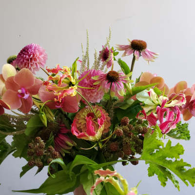Loose bouquet of pink and peach orchids, dahlias, and mixed flowers with berries.