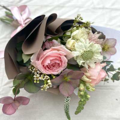Pink and white bouquet wrapped in brown paper with a ribbon