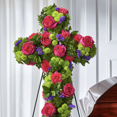 Cross-shaped floral tribute with pink roses and green pompons