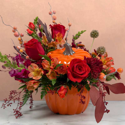 Pumpkin-shaped vase filled with red and orange flowers