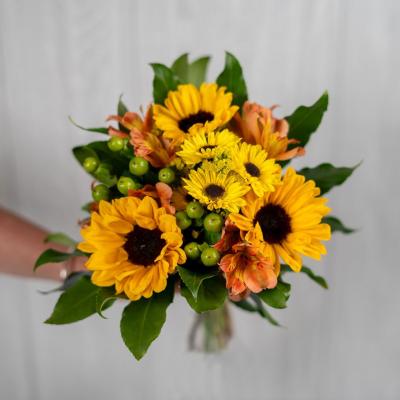Bouquet of yellow sunflowers and orange flowers with green berries