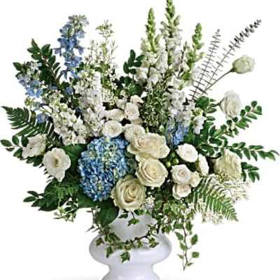 White and blue floral arrangement in a white pedestal vase