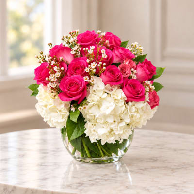 Pink roses and white hydrangeas arranged in a clear glass vase