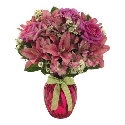 Pink roses and lilies in a red glass vase with a green ribbon