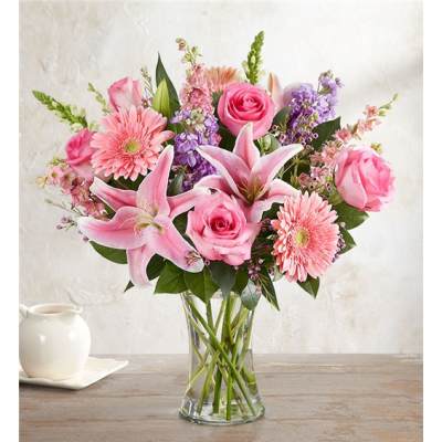 Pink roses, lilies, and gerbera daisies in a clear glass vase