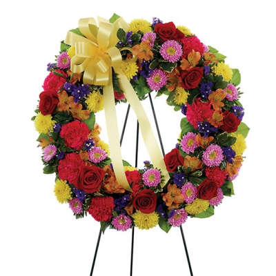 Colorful floral wreath on a stand with a yellow bow