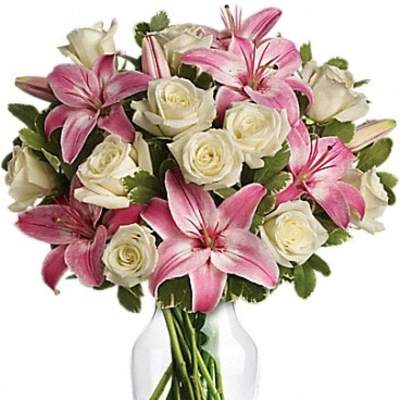 Pink lilies and white roses arranged in a clear glass vase