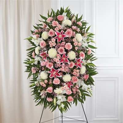 Standing floral spray with pink roses, white blooms, and lilies on an easel